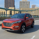 An orange Hyundai Tucson SUV drives across a bridge